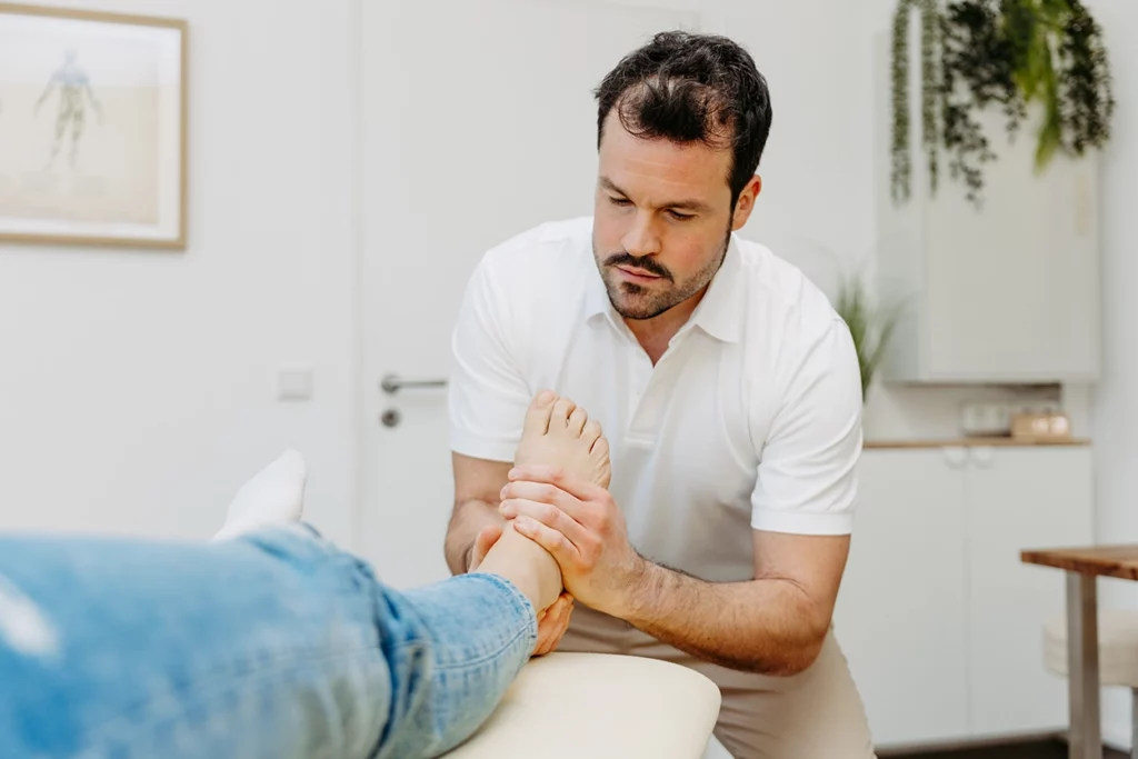 Osteopath Tim Dorniak bei einer Behandlung am Fuß.